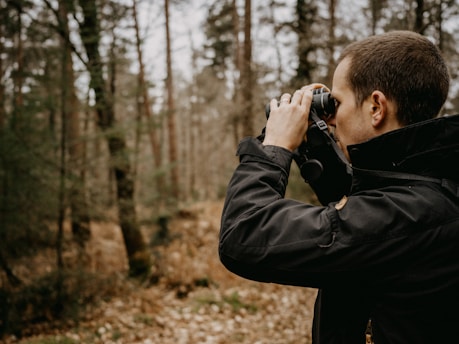 a man taking a picture of a forest with a camera