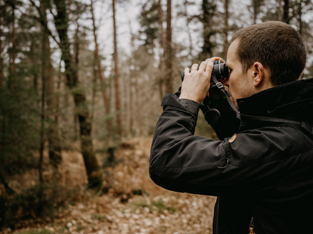 a man taking a picture of a forest with a camera