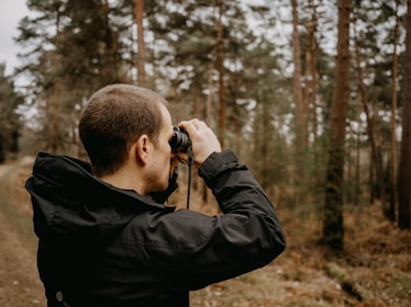 A forest officer using binoculars and a spotting scope during a rescue mission.