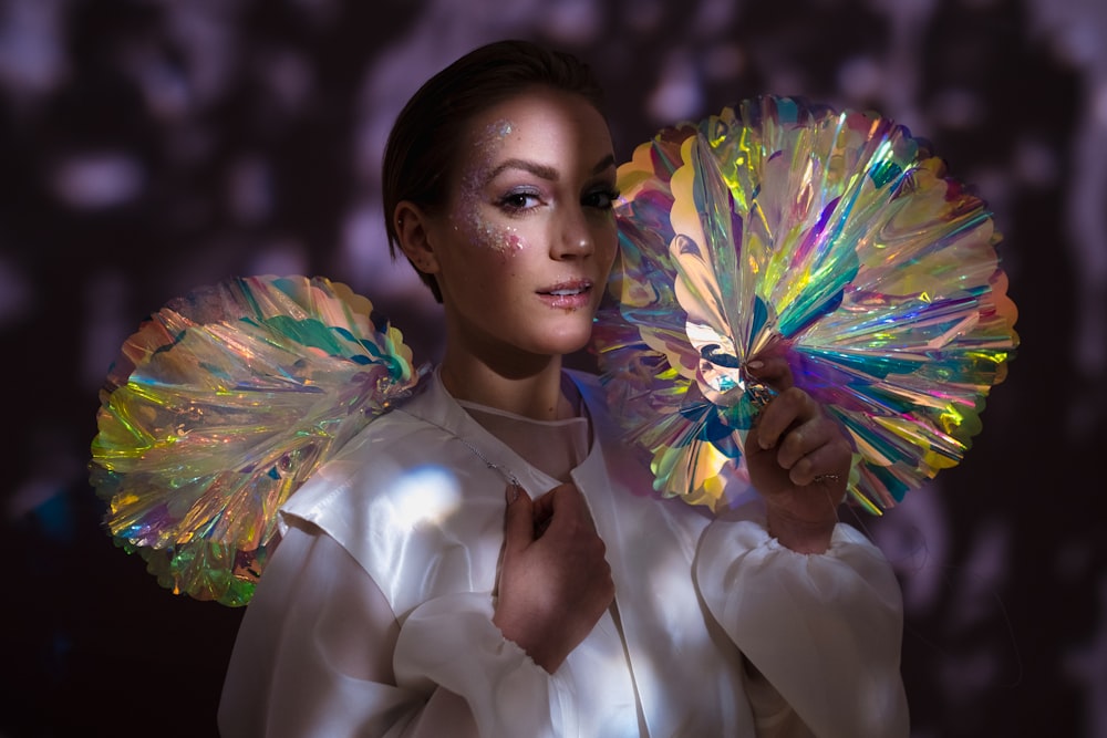 a woman in a white shirt holding a colorful fan