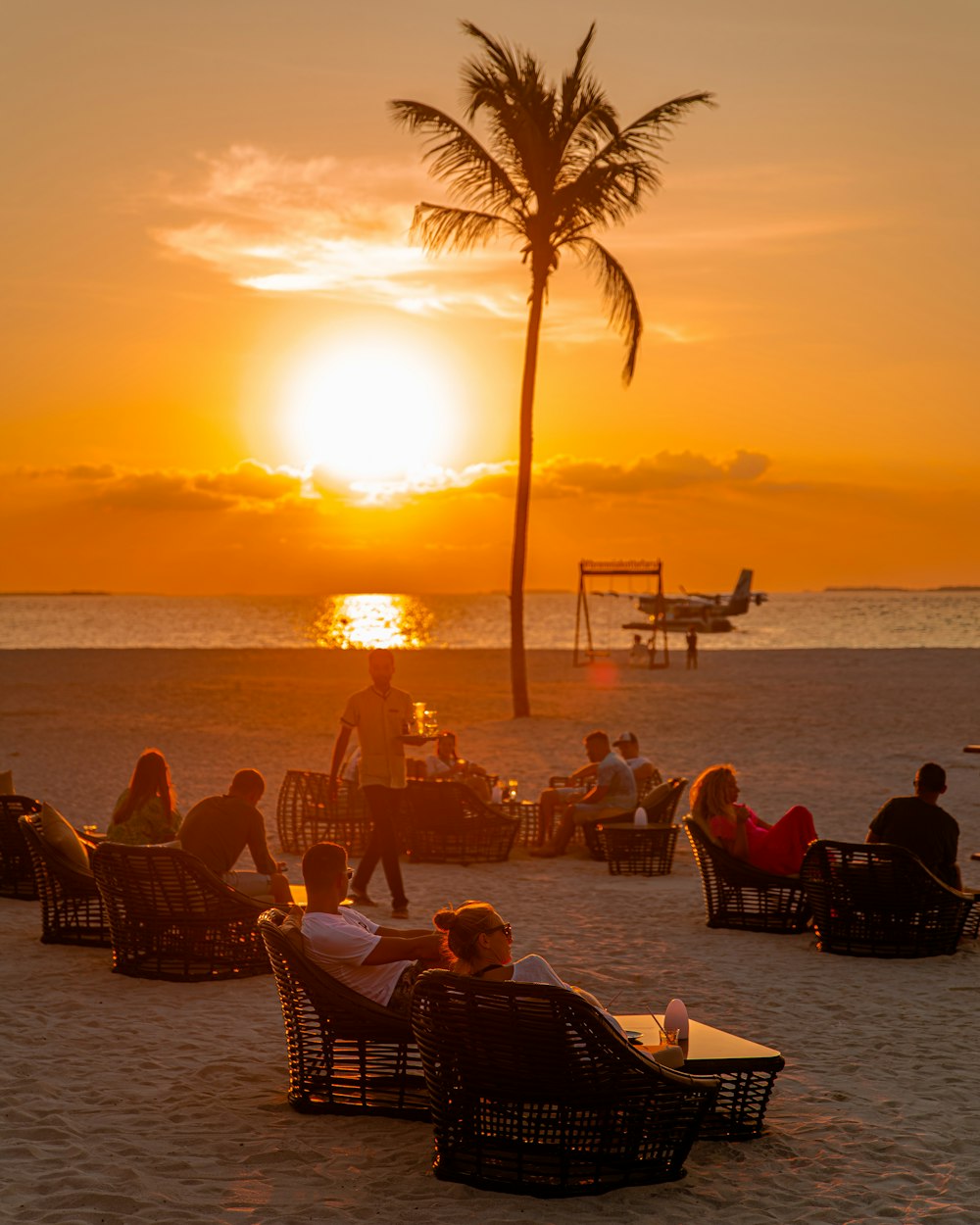 a group of people sitting on top of a sandy beach