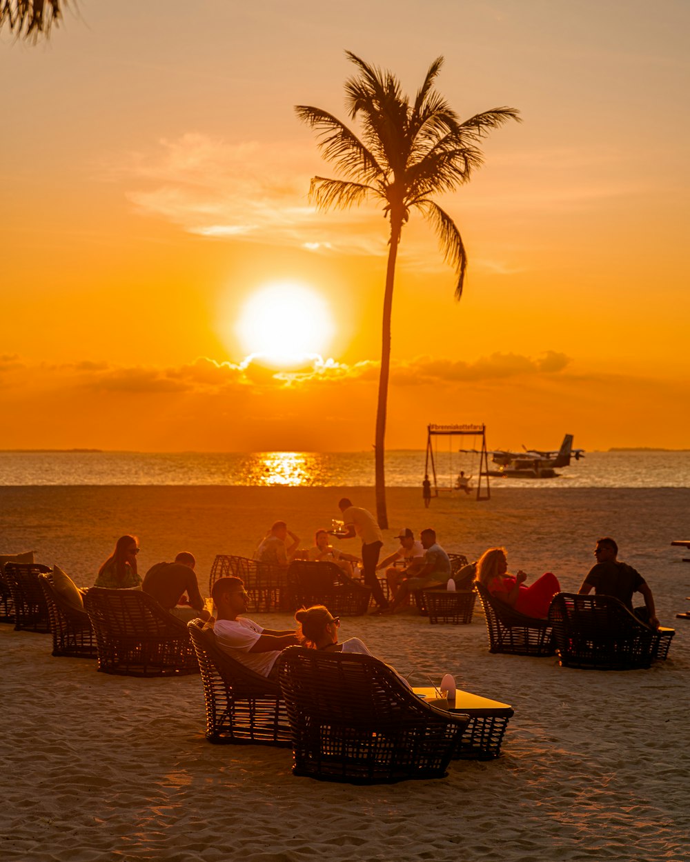 a group of people sitting on top of a sandy beach