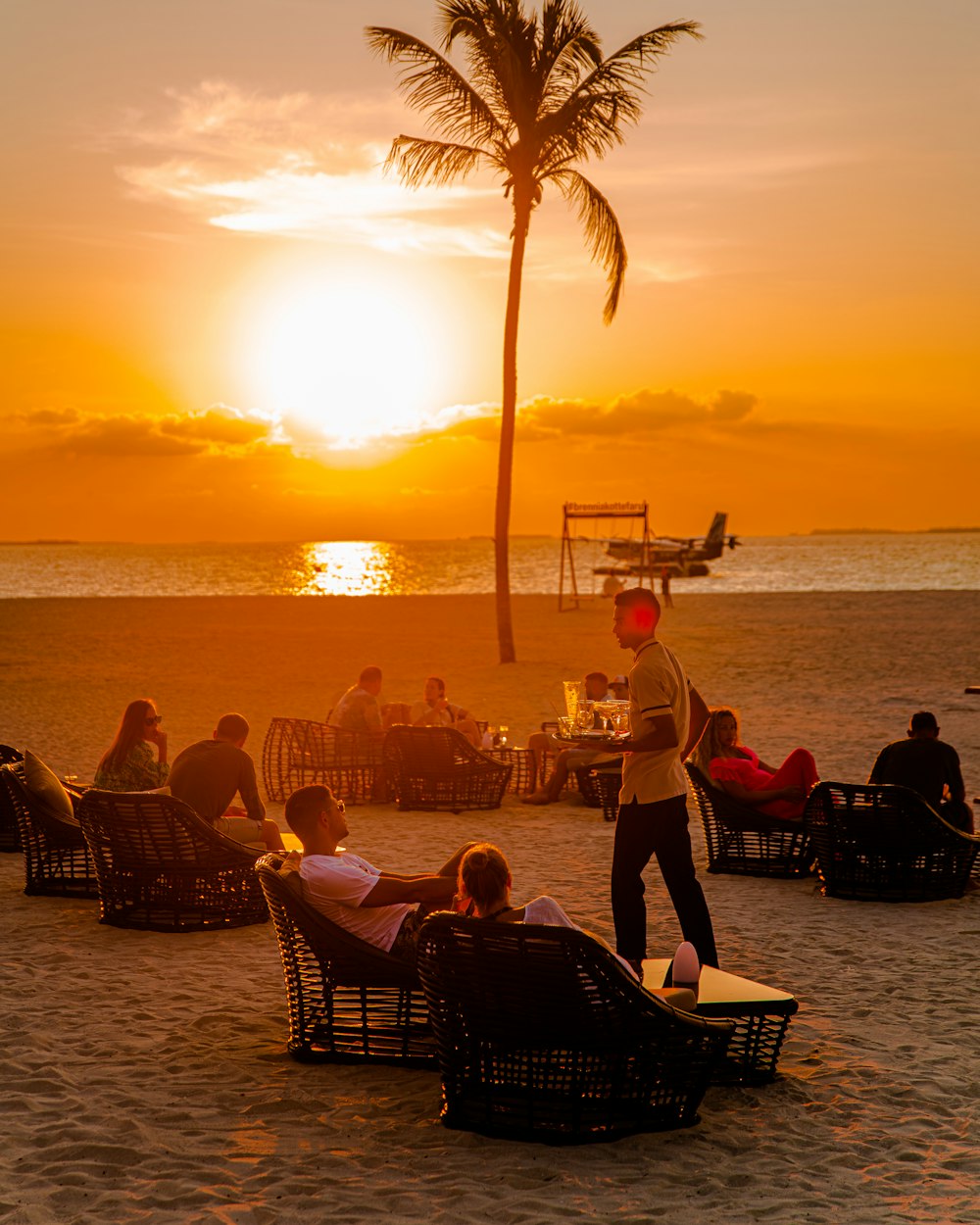 a group of people sitting on top of a sandy beach