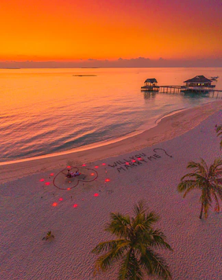 A serene beach at sunset with a wedding arch decorated in flowers, inviting couples to imagine their special day.