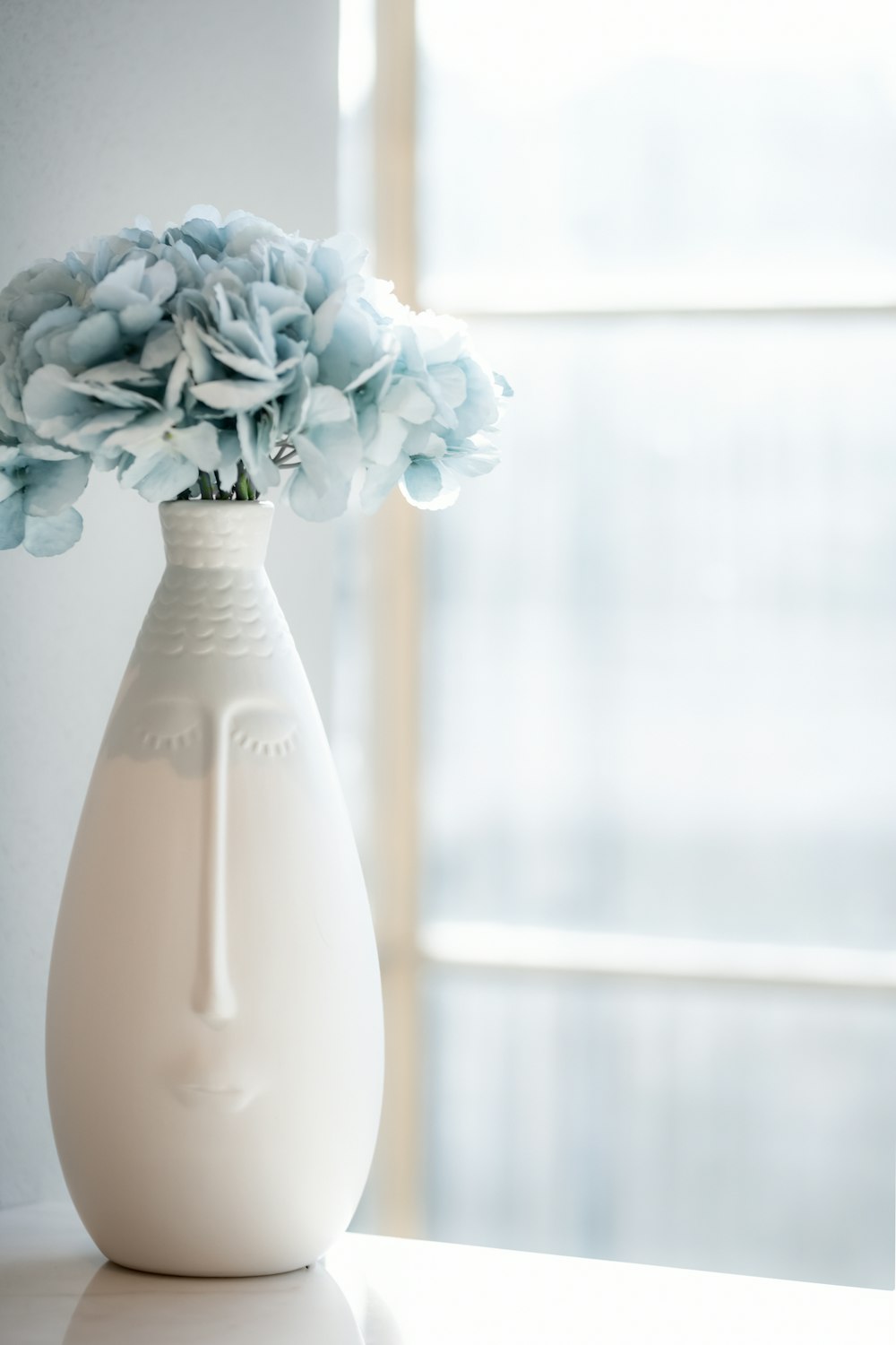 a white vase filled with blue flowers on top of a table