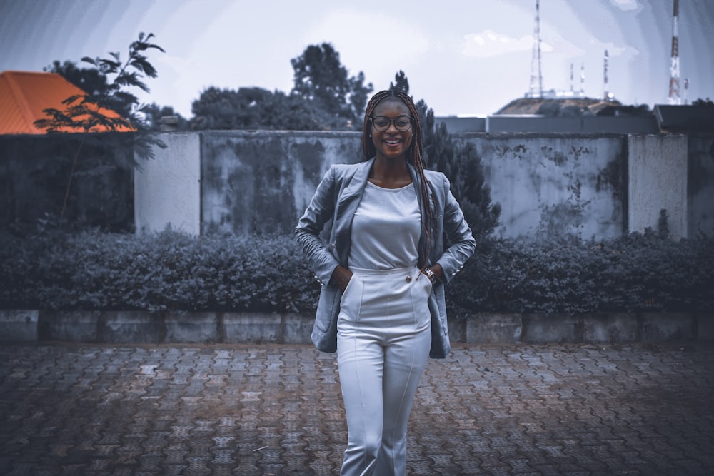 a woman in a white jumpsuit walking down a brick walkway