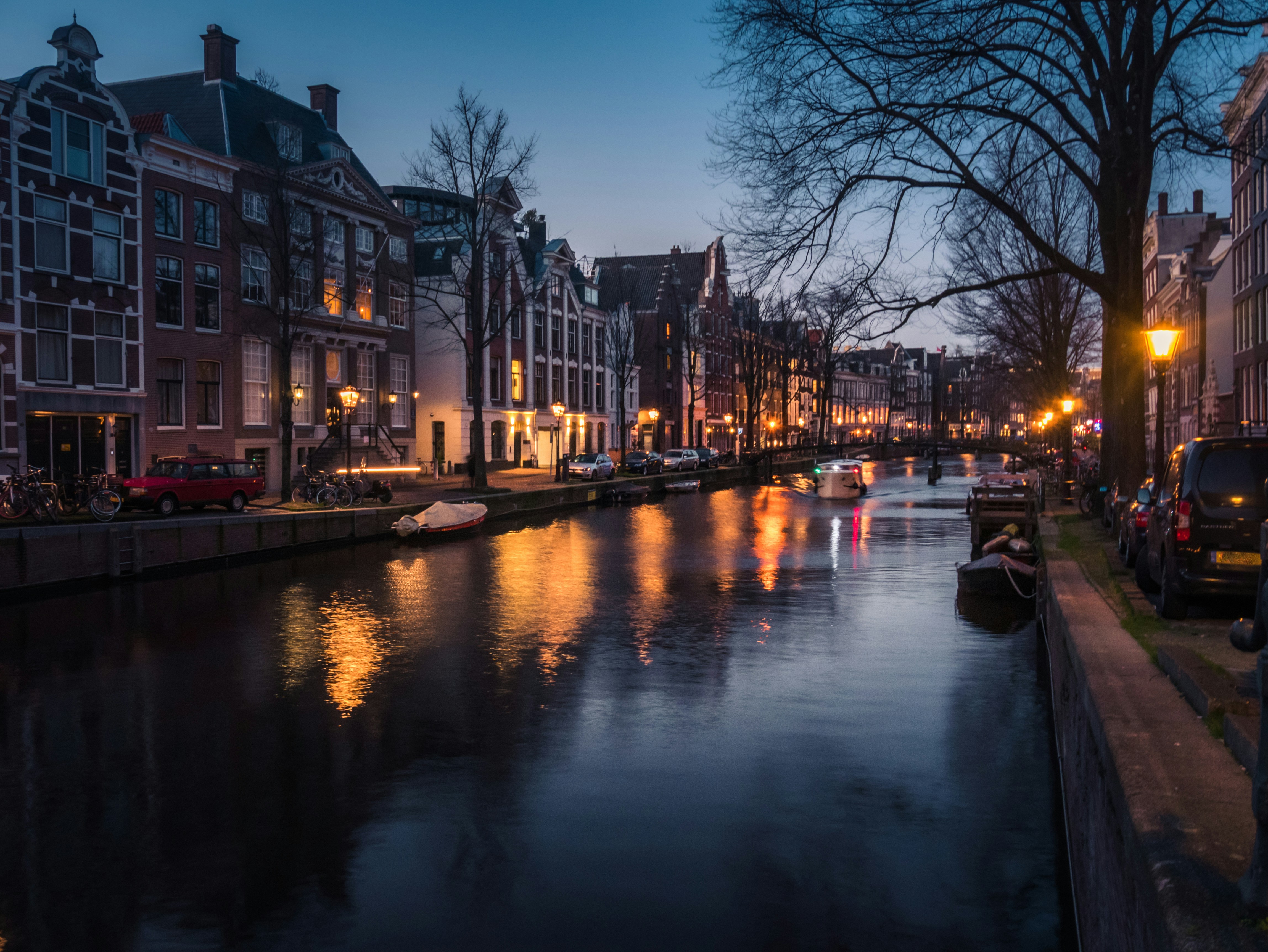 a river running through a city next to tall buildings, Amsterdam canal during dusk time