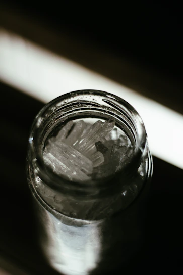 Close-up of a crystal jar filled with authentic Ibiza sand, resting on a smooth white surface with soft natural light.