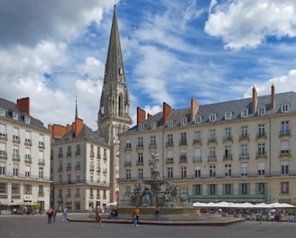 a large building with a tower and a fountain in front of it