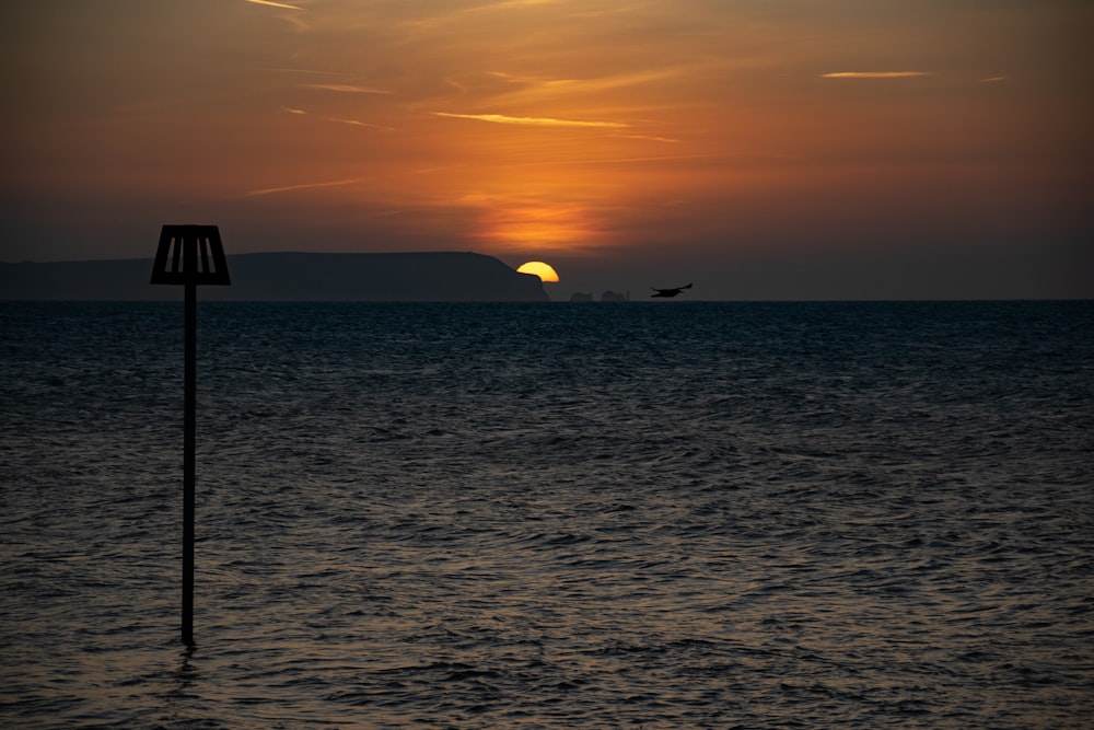 the sun is setting over the ocean with a boat in the distance