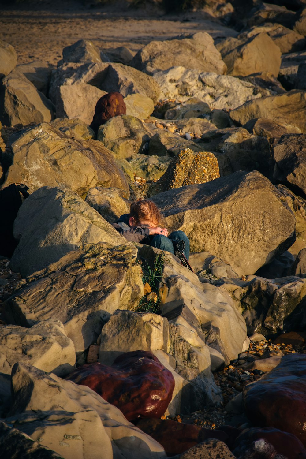 a young boy sitting on a pile of rocks