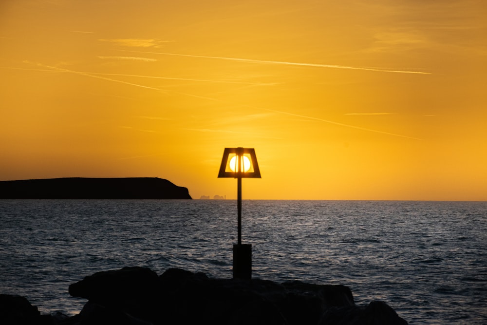 a lamp post sitting on the edge of a body of water