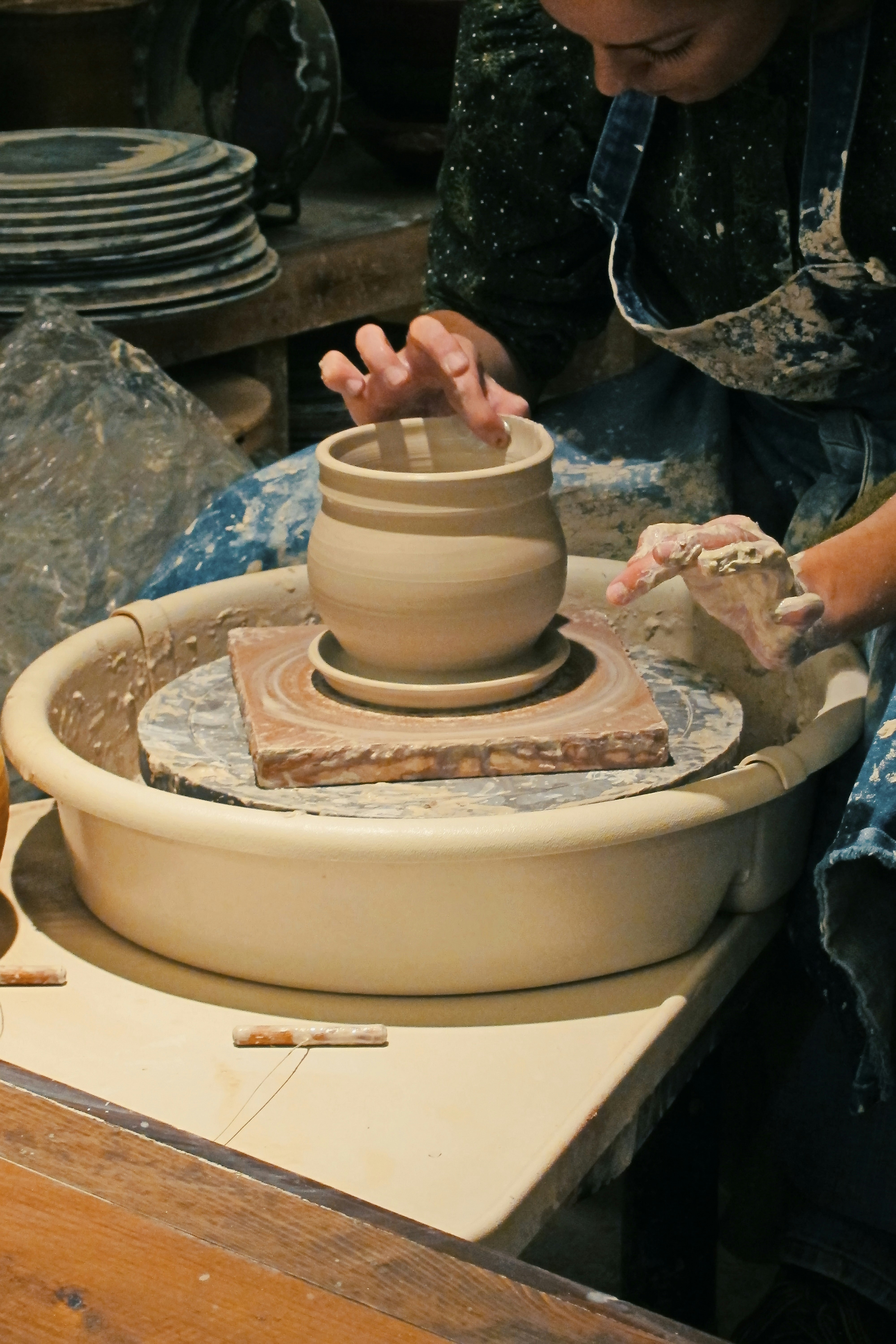 a woman is making a vase out of clay