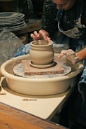 An artist working on a ceramic piece with glaze.