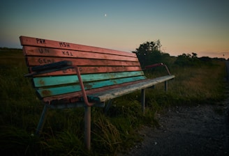 a wooden bench sitting on top of a grass covered field