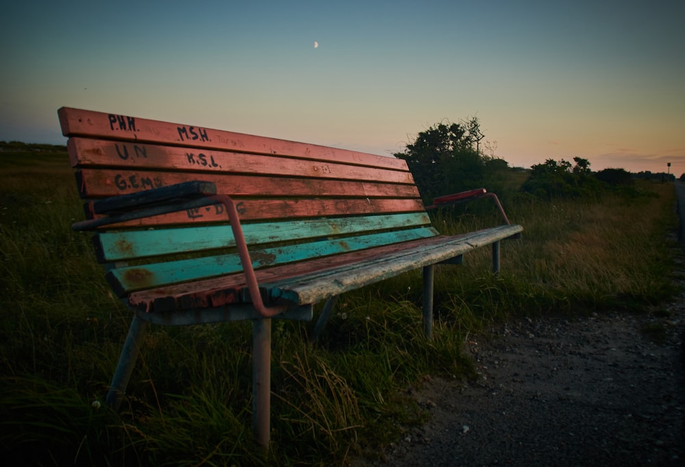 a wooden bench sitting on top of a grass covered field