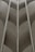 A symmetrical architectural design featuring curved gray panels with vertical metallic lines running through them. The pattern creates a sense of depth and repetition, showing sleek and modern aesthetics.