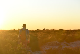 A traveler with a backpack consulting a map on a scenic mountain trail during golden hour.