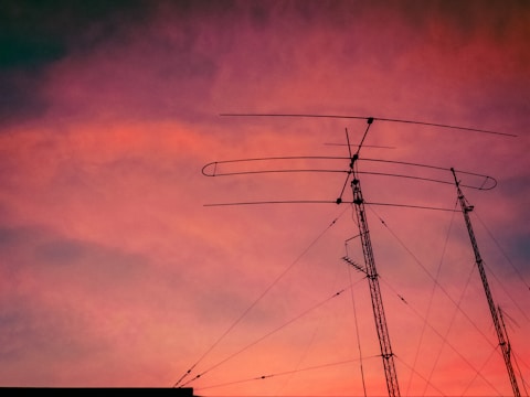 A backyard ham radio station with antennas stretching into a clear blue sky at sunset.