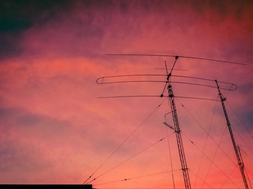 A cozy ham radio station setup with antennas visible outside a window during sunset.