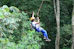 a man riding a zip line in the middle of a forest