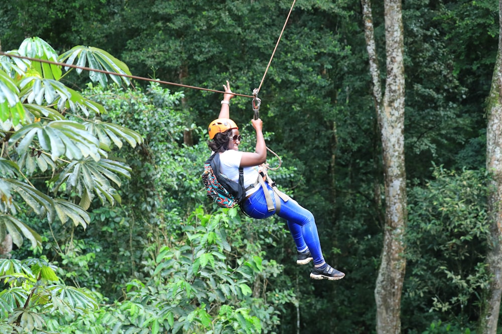 a man riding a zip line in the middle of a forest