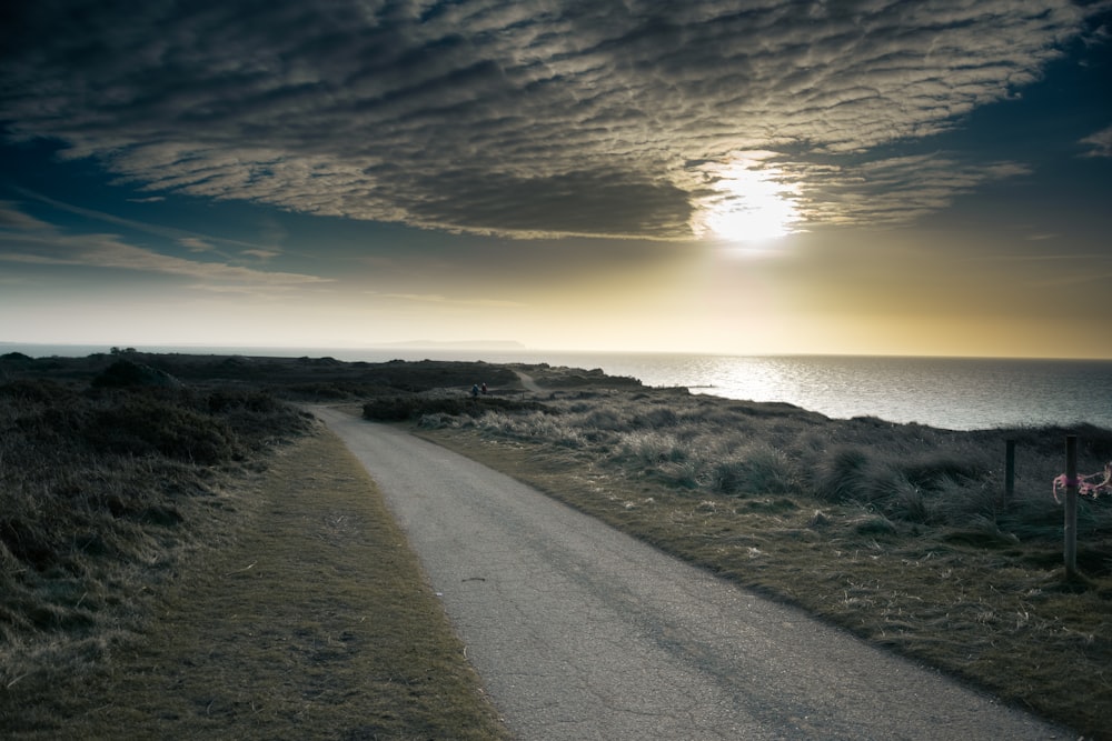 the sun is setting over the ocean on a cloudy day