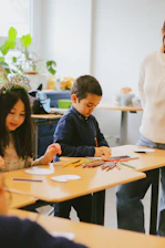 a group of children sitting at a table working on crafts