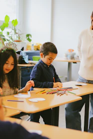 a group of children sitting at a table working on crafts