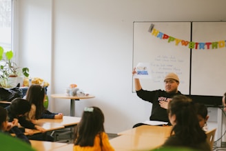 a man standing in front of a whiteboard in a classroom
