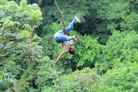 a man riding a zip line in the middle of a forest
