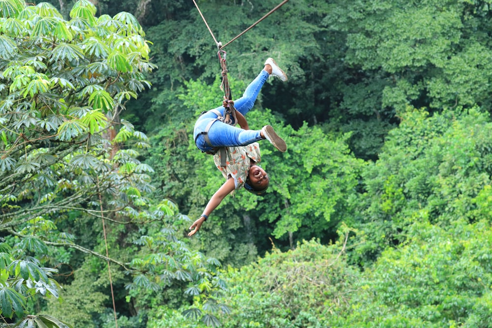 a man riding a zip line in the middle of a forest