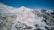 Snow-covered mountain cabins with skiers enjoying fresh powder under a clear blue sky.