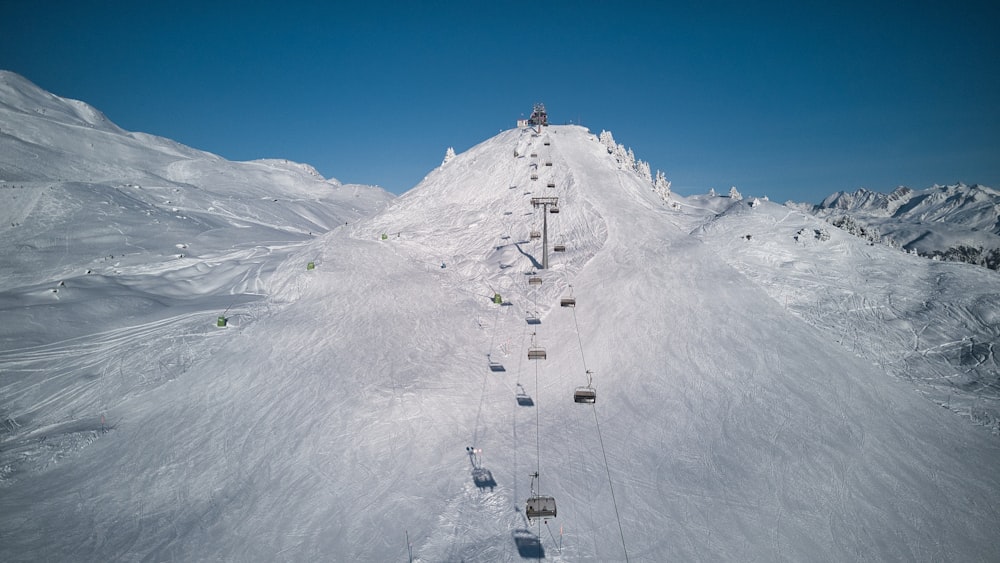 um teleférico subindo o lado de uma montanha coberta de neve