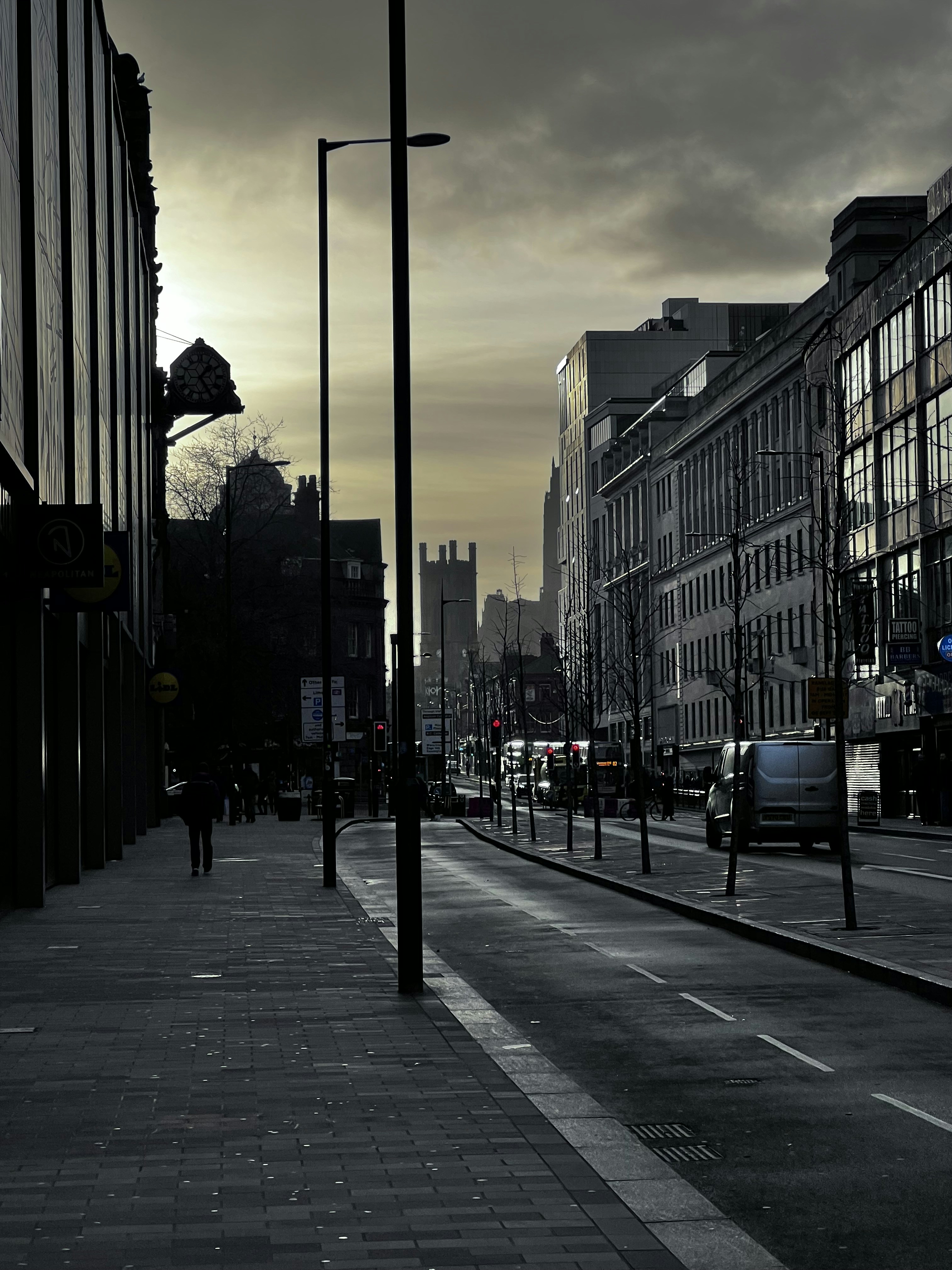 Person walking alone on empty street in overcast weather, distant perspective, sense of isolation