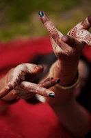 Stylish mehendi patterns on hands at a lively party setting with colorful decorations.