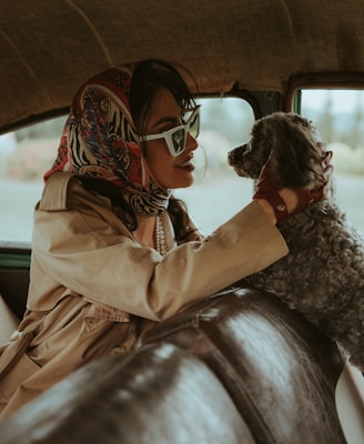 a woman sitting in a car holding a dog