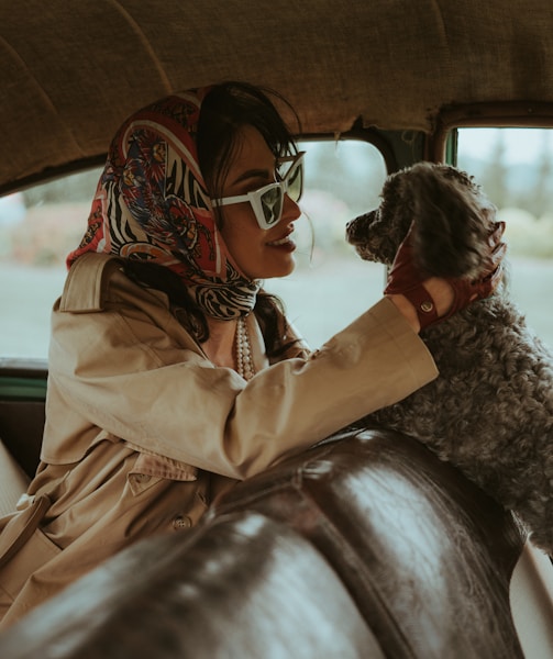 a woman sitting in a car holding a dog