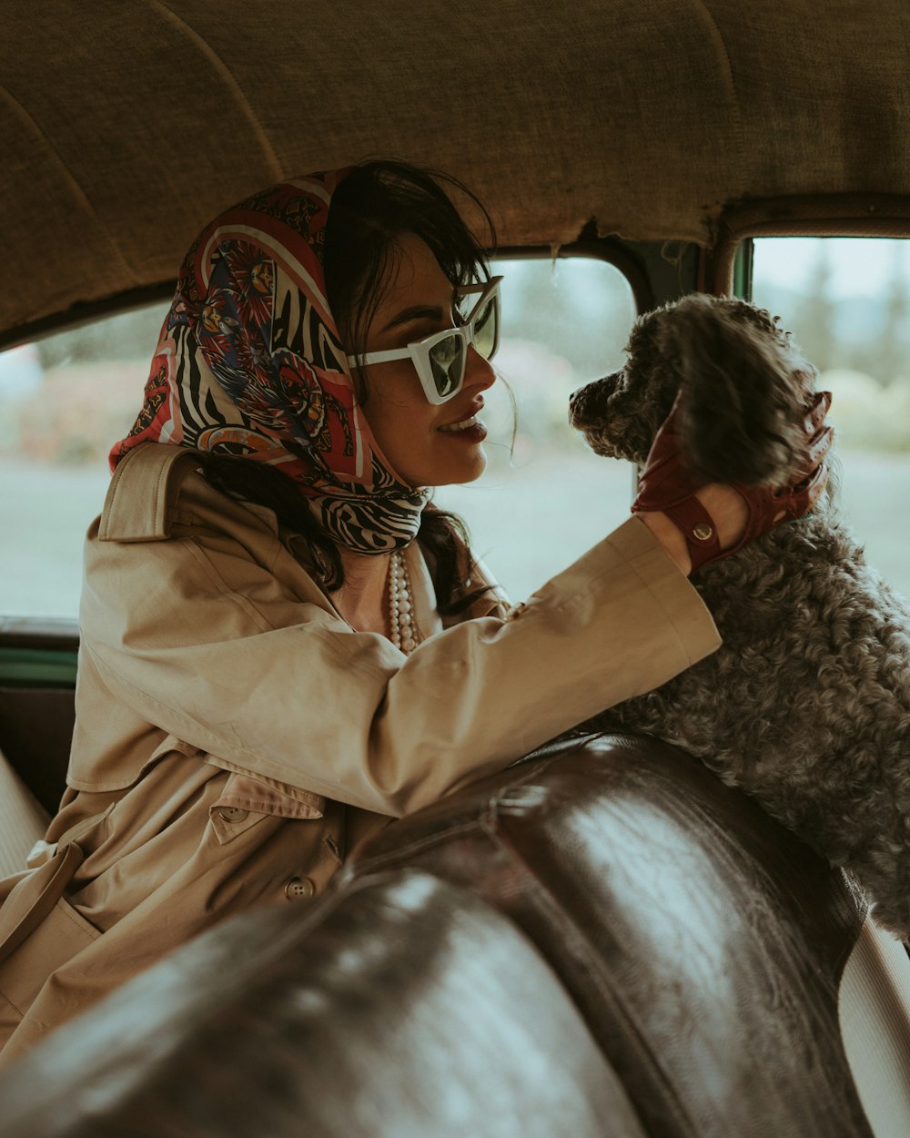 a woman sitting in a car holding a dog