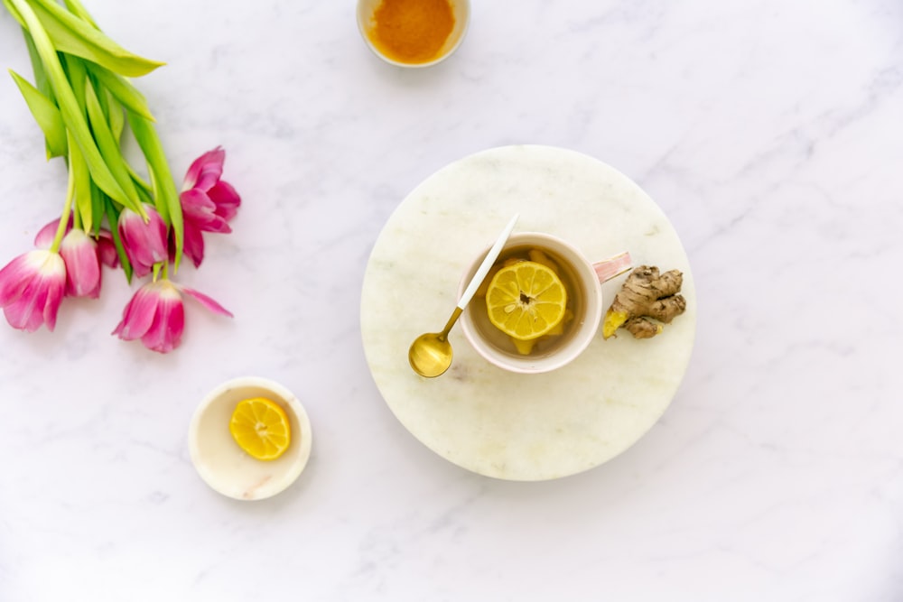a marble table topped with a bowl of lemons and a cup of tea