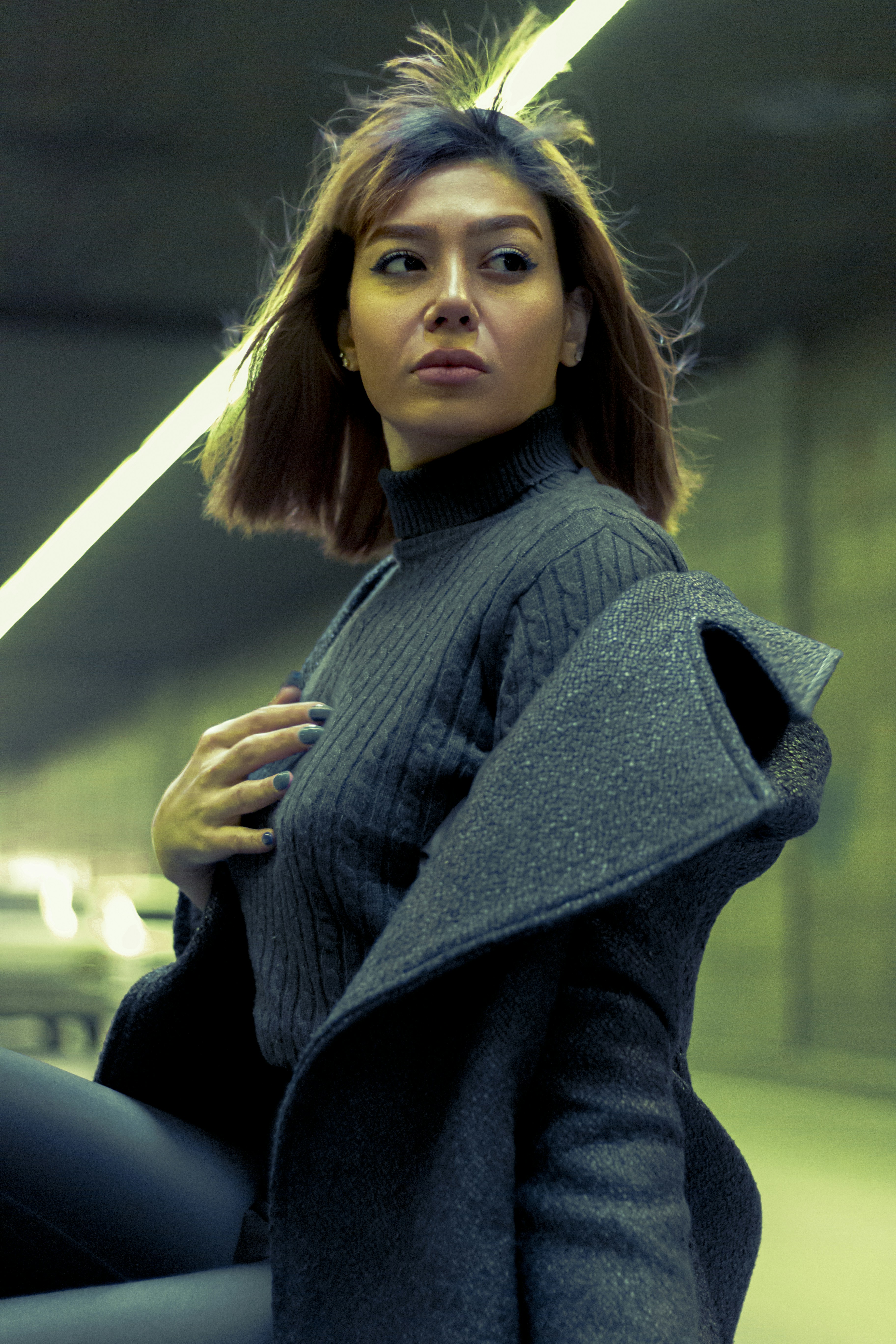a woman standing in a parking garage with her hand on her hip