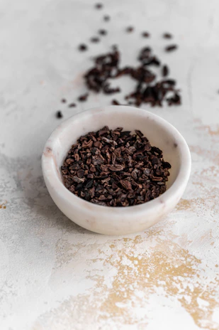 Close-up of cacao nibs and cacao pulp in rustic bowls on a wooden surface.