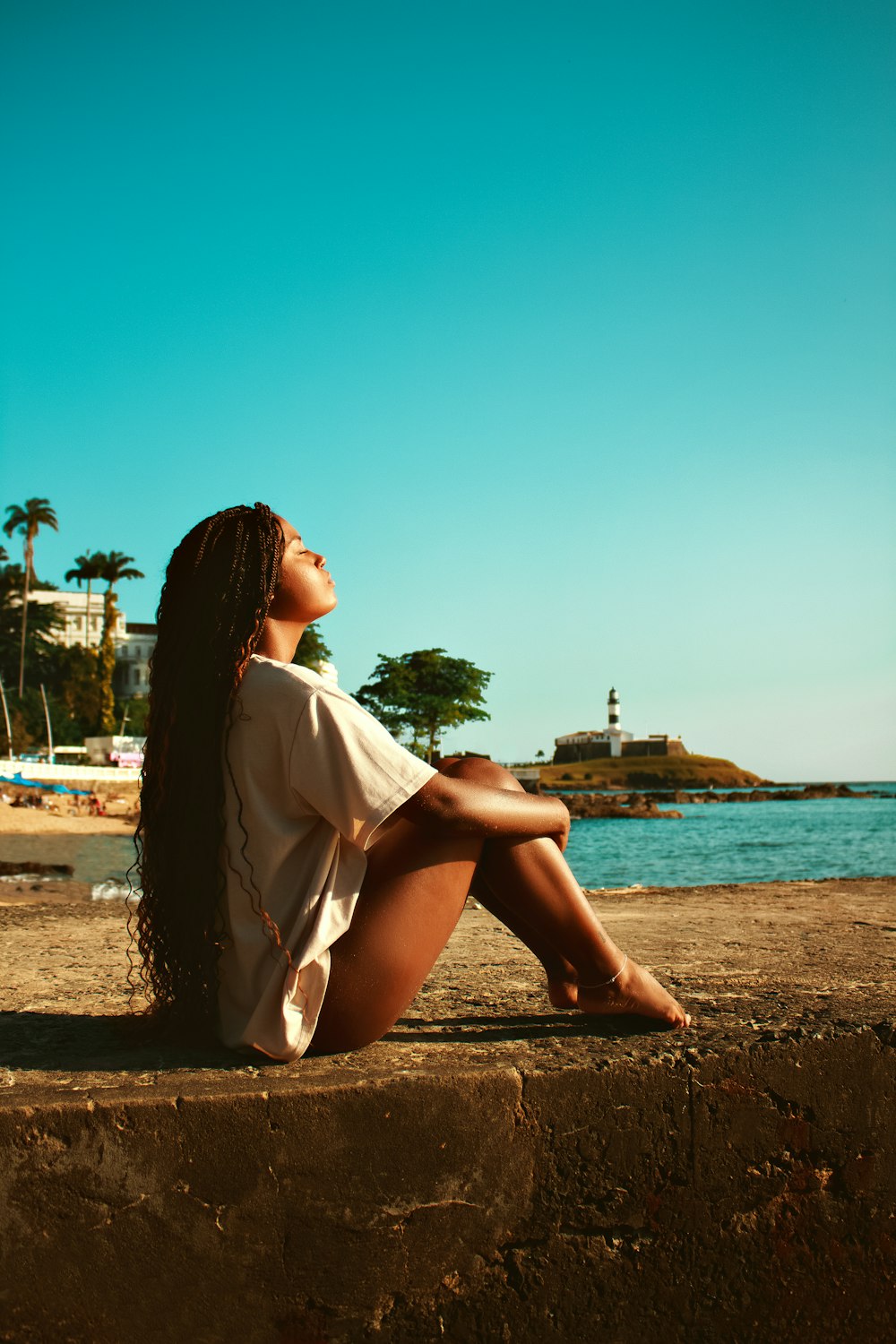 a woman sitting on a wall looking up at the sky