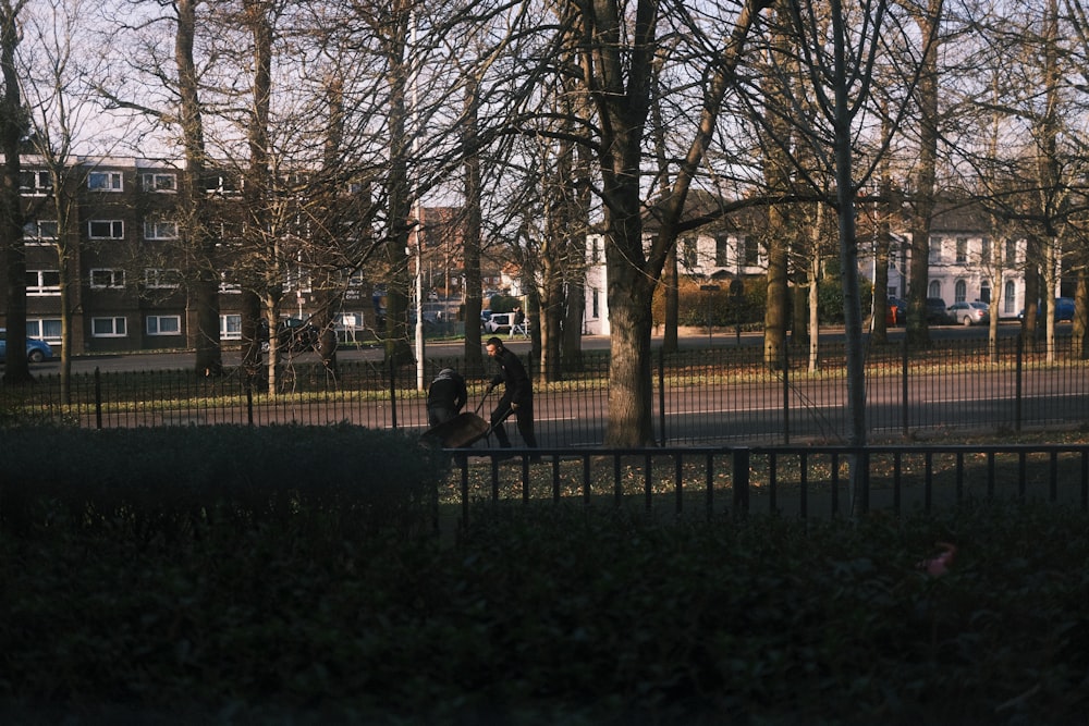 a couple of people walking down a street next to a fence