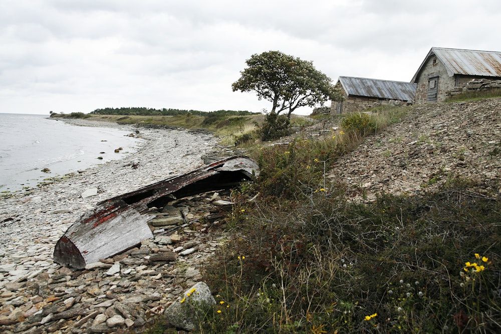 an old boat sitting on a rocky shore next to a body of water