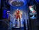 A high-tech suit displayed in a futuristic setting, illuminated by focused lighting. The surroundings include digital screens showing technical data and designs related to the suit. The environment appears to be a lab or exhibit with metallic and technological elements.