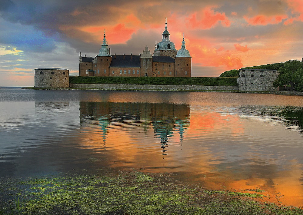 a large castle sitting on top of a lake under a cloudy sky