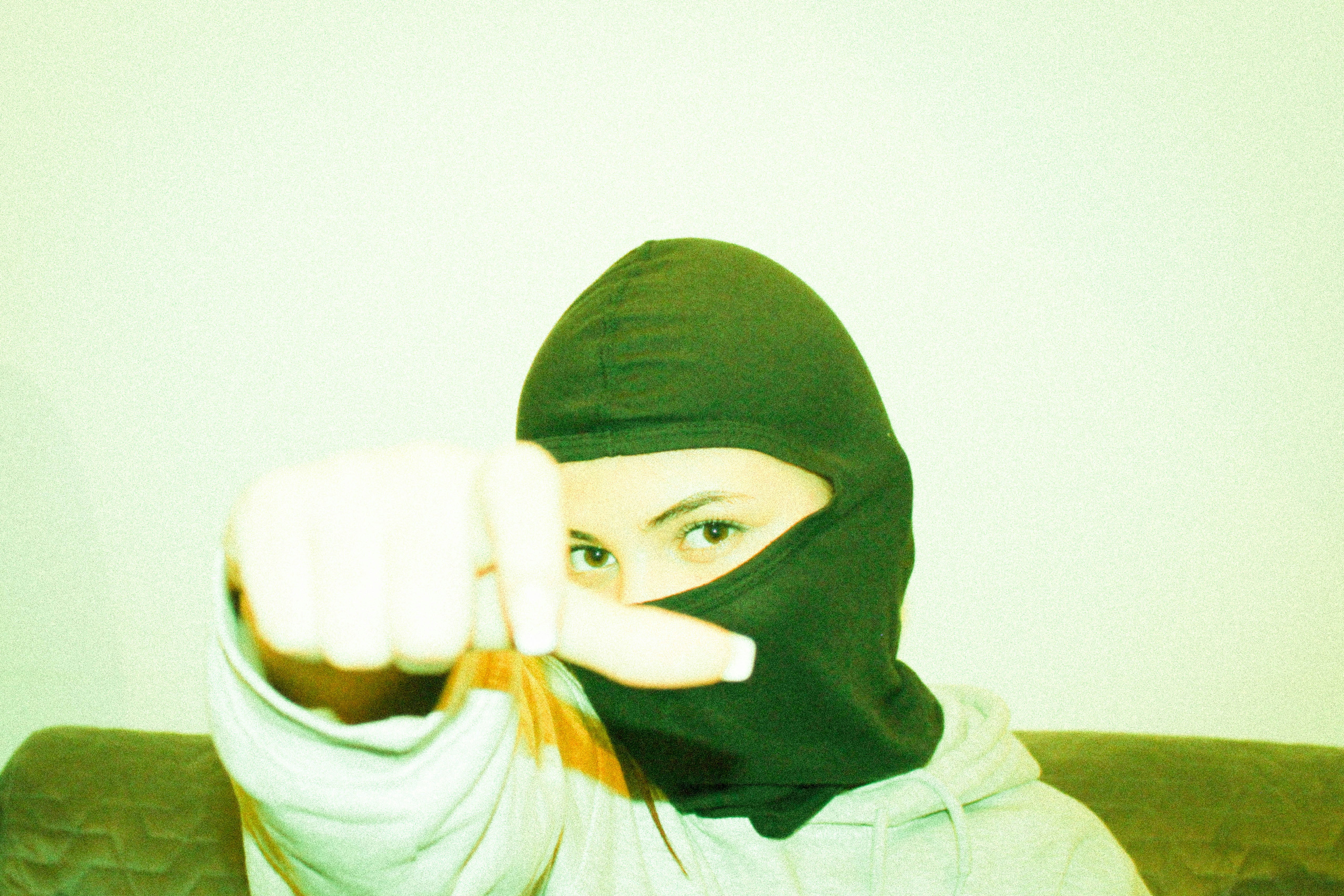 a woman wearing a black mask pointing at the camera