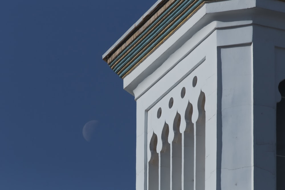 a clock tower with a half moon in the background