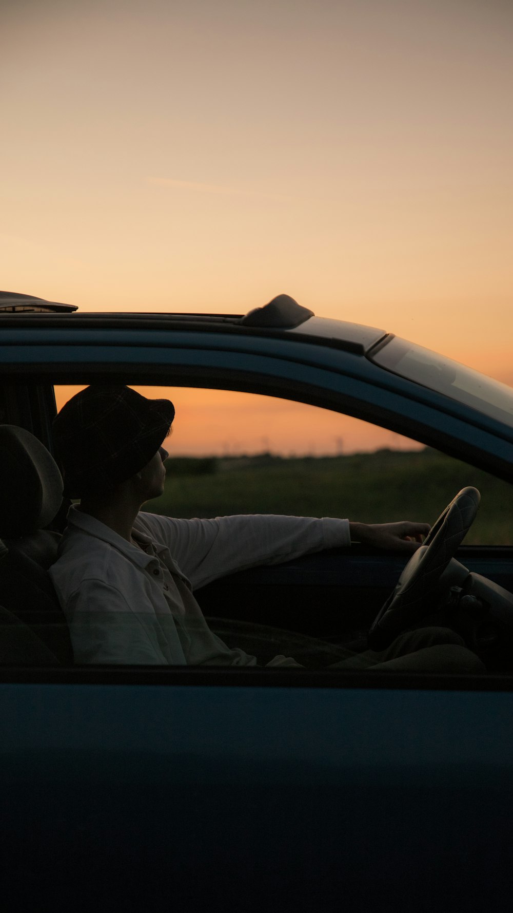 a person sitting in a car at sunset
